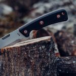 Fixed blade knife with stainless steel blade in stump on camping trip